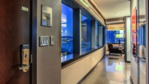 A hotel corridor with a view of the city at night, a reception desk, and a seating area. - City Center! | Panoramic Corner Suite at Vdara (Las Vegas)