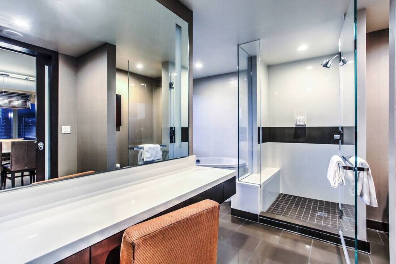 Une salle de bain moderne dotée d’un grand miroir, d’une douche et d’un meuble-lavabo avec un long plan de travail.