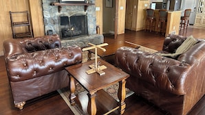 Una sala de estar con sofás de cuero, una mesa de centro de madera, una chimenea y una pared decorativa de piedra.