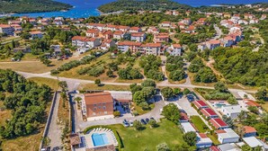Vue aérienne d’un quartier résidentiel situé sur la côte, avec des maisons, une piscine et une route.