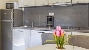 Une cuisine moderne équipée d’appareils électroménagers en acier inoxydable, d’une machine à café et d’une plante en pot posée sur le plan de travail.