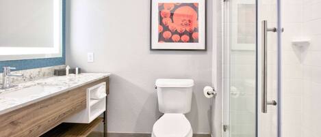 A modern bathroom with a marble vanity, a toilet, and a glass shower enclosure.