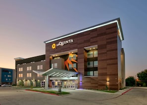 Un hotel de diseño moderno, con un llamativo logo de sol y el nombre 'La Quinta' en la fachada.