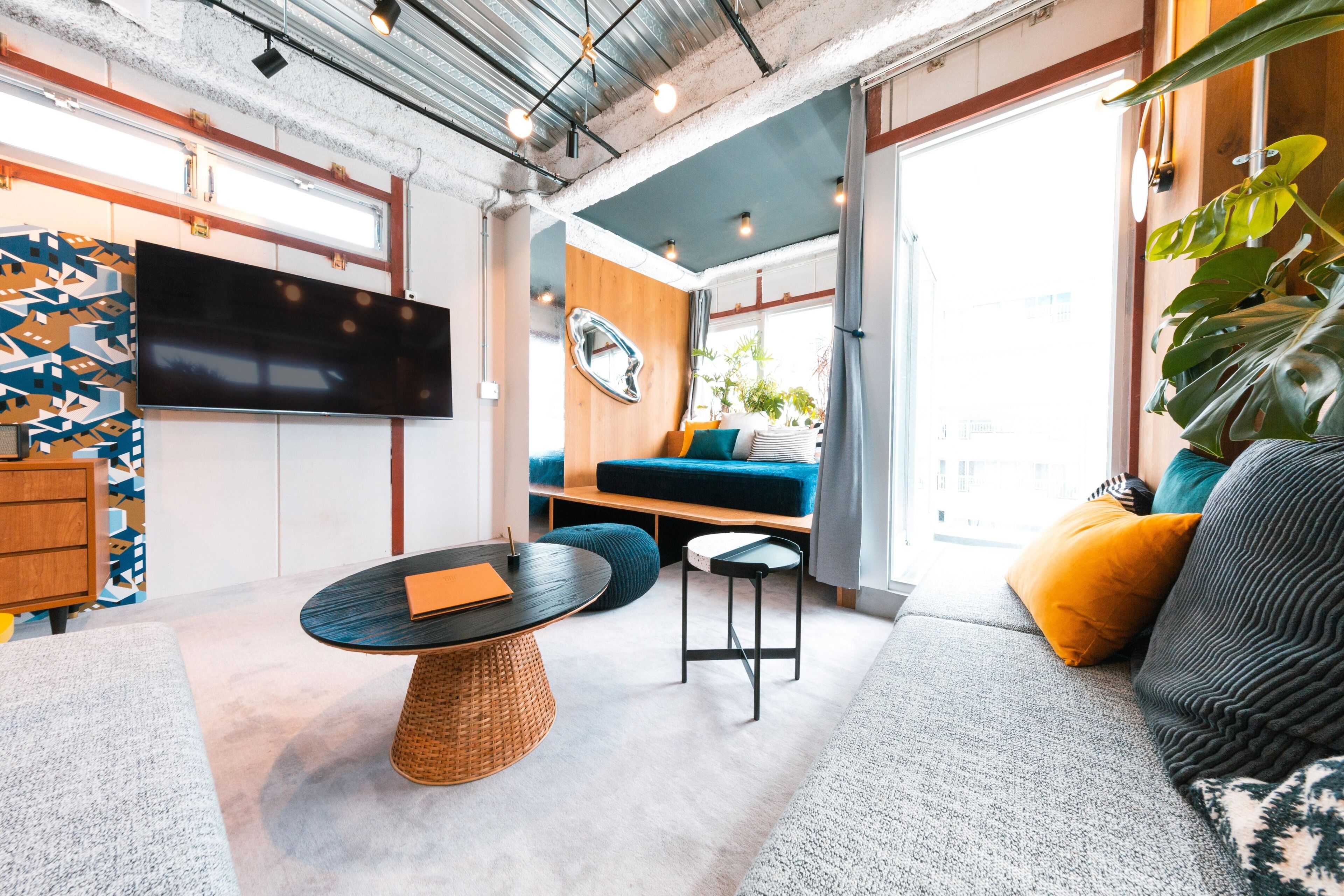 A modern living room with a large TV, a round coffee table, a sofa, and a dining table.