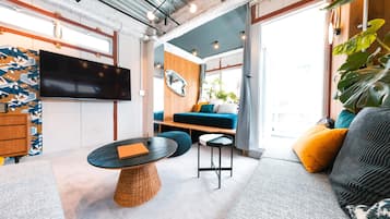A modern living room with a large TV, a round coffee table, a sofa, and a dining table.