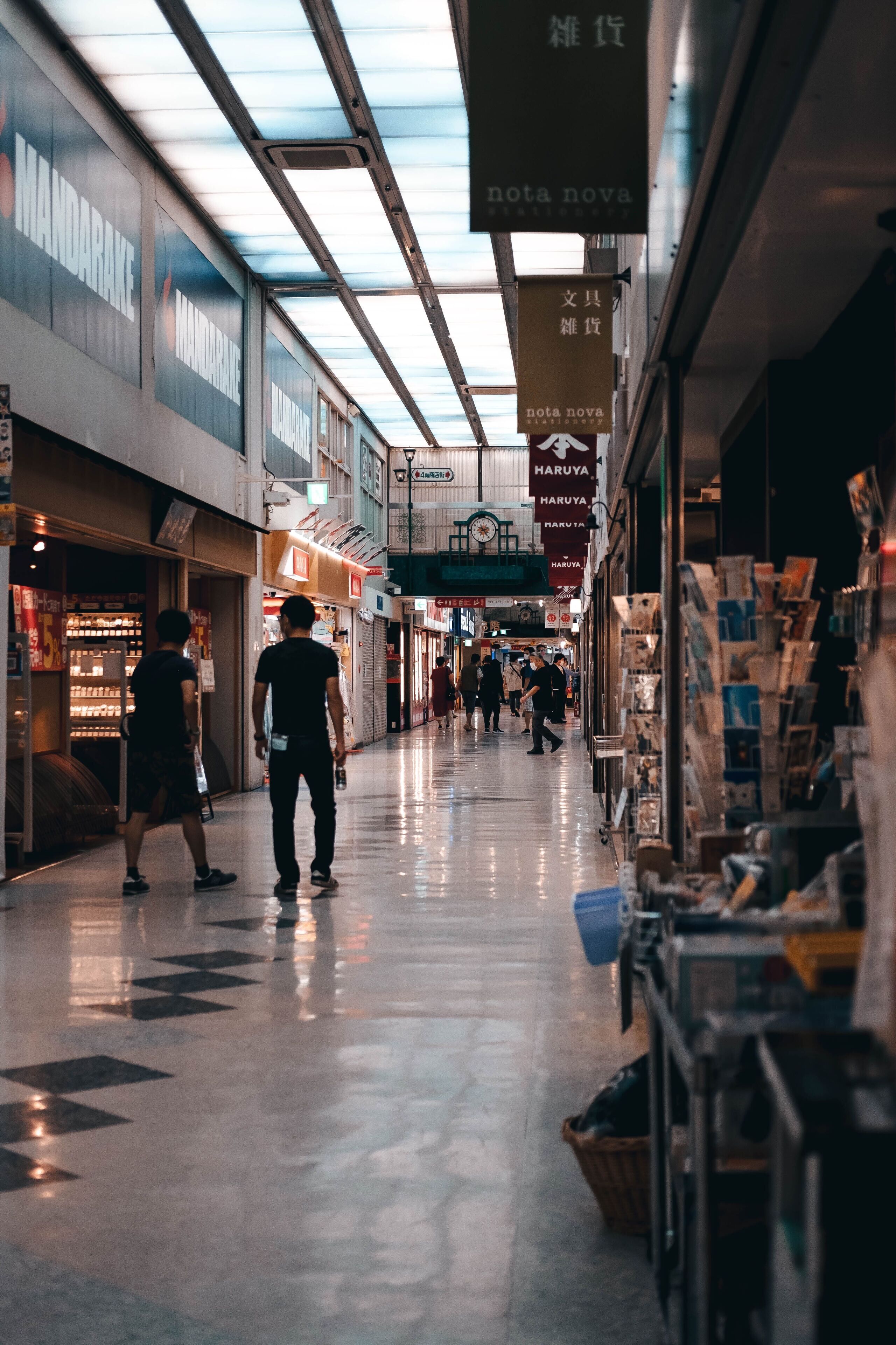 A corridor with shops on either side, overhead signs, and a reflective floor.
