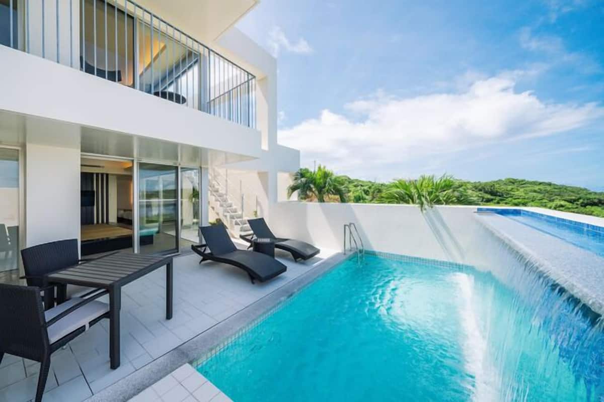 A modern poolside area with a clear view of the sky, a pool, and a building with a balcony.