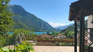 A patio with stone flooring, a metal fence, and a view of a lake and mountains.