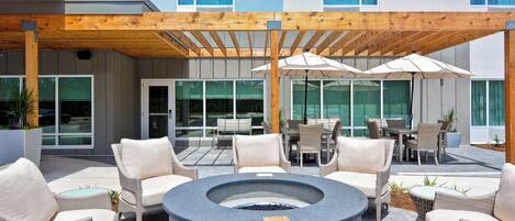 An outdoor patio with wicker furniture, a circular seating area, and umbrellas.
