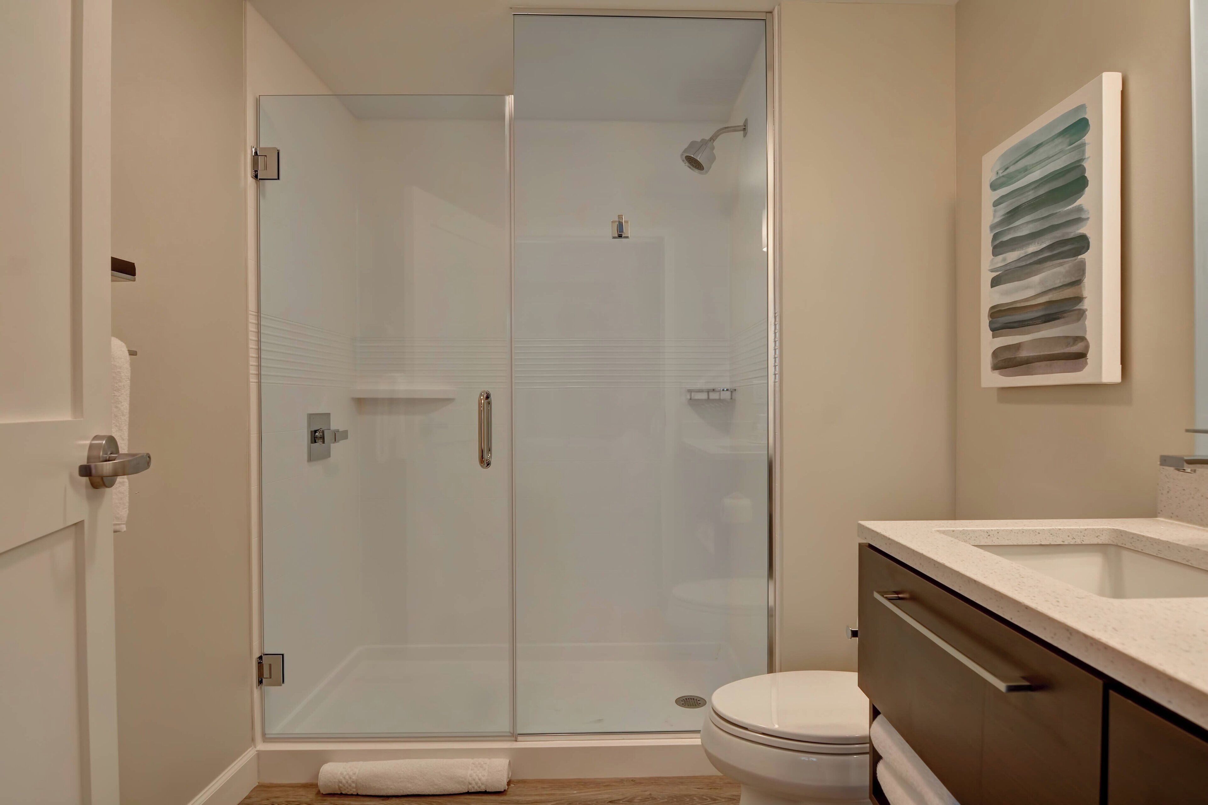 A modern bathroom with a glass shower enclosure, a toilet, and a vanity with a sink.