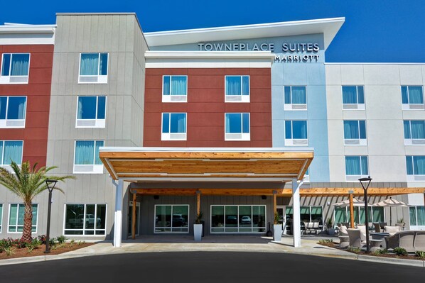 A modern hotel with a covered entrance, multiple floors, and a sign reading "TOWNEPLACE SUITES MARRIOTT".