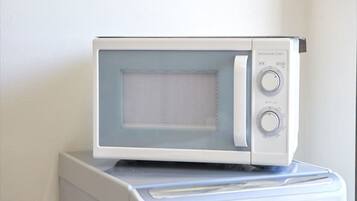 A microwave oven placed on top of a washing machine.