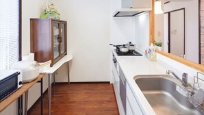 Una cuina compacta amb fogó, rentapelats i armari de fusta.