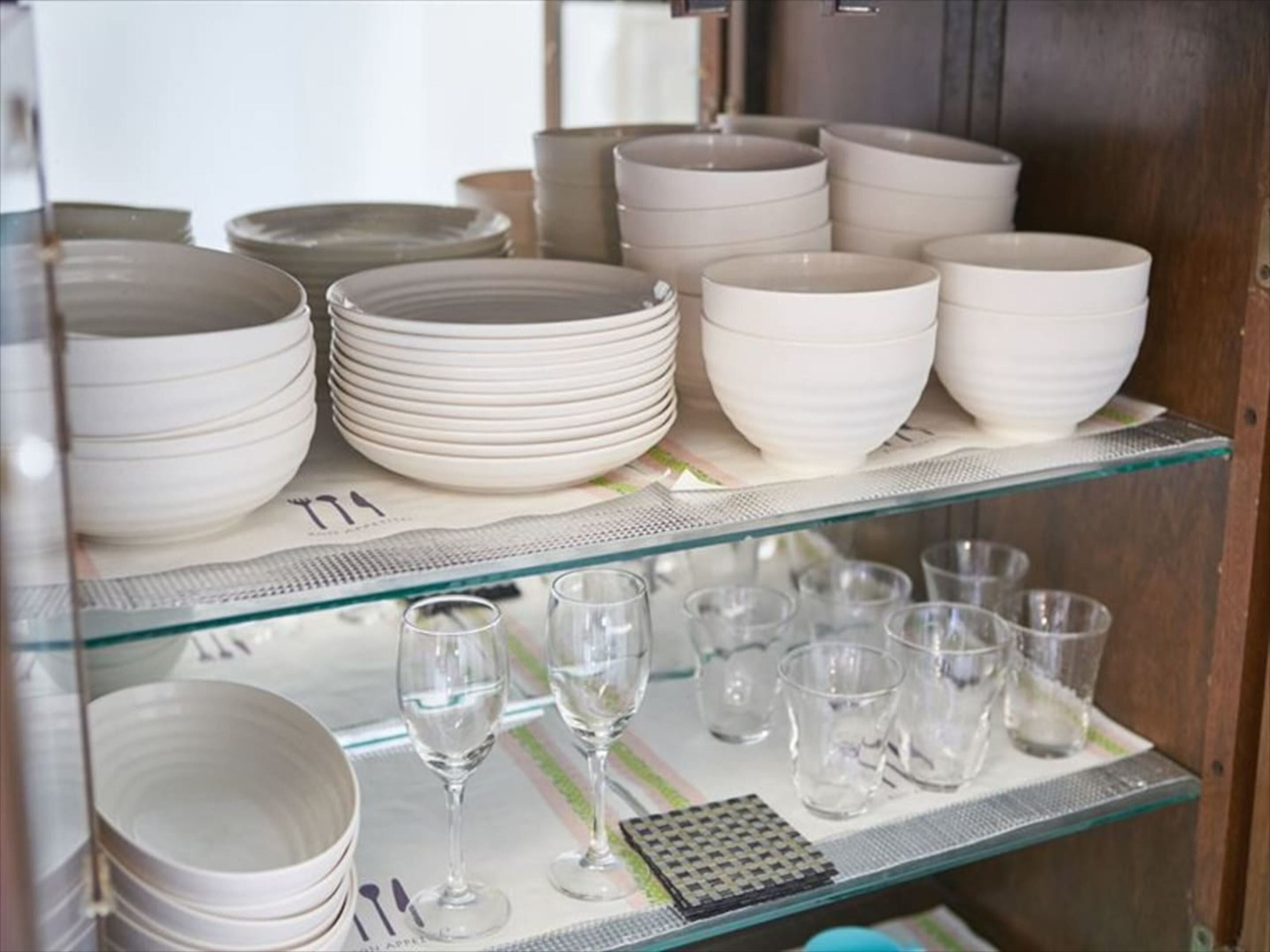 Une collection d’assiettes et de bols en céramique blanche est exposée sur des étagères.