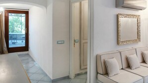 Un couloir avec un canapé, une porte donnant sur un balcon et un appareil de climatisation fixé au mur.