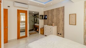 Een moderne slaapkamer met een bed, een kaptafel met spiegel, een televisie en een ingelijste quote aan de muur.