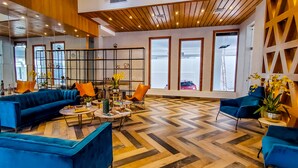 Een moderne zithoek met blauwe banken, houten vloeren en een decoratieve wand.