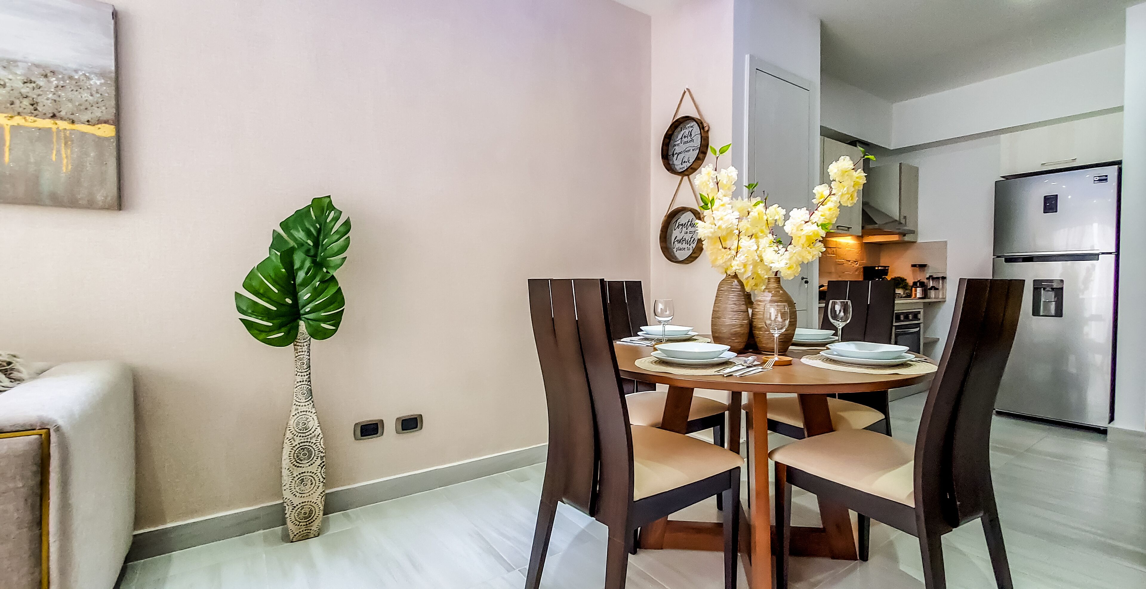 A modern dining area with a round table, dark chairs, and a vase of flowers.