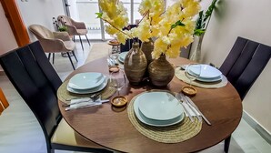 Een eettafel gedekt met borden, bestek en vazen met bloemen.