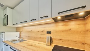 Una cucina moderna con mobili in legno, un bollitore in acciaio inossidabile e un piano cottura a induzione integrato.