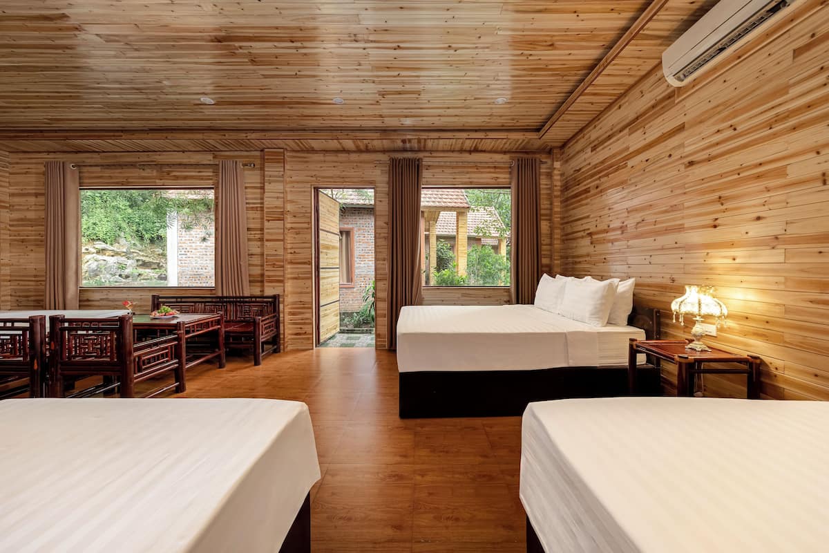 A wooden room with two beds, a dining table, and chairs.