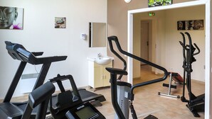 Zona de ejercicios con cintas de correr y bicicletas estáticas, un lavamanos y un espejo.
