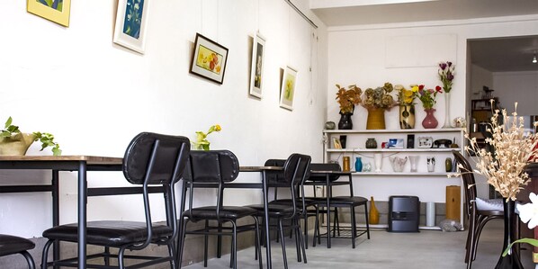 A dining area with black chairs, a wooden table, and a shelf with various vases and plants. - Guest Cafe Kuchikumano (Kamitonda)