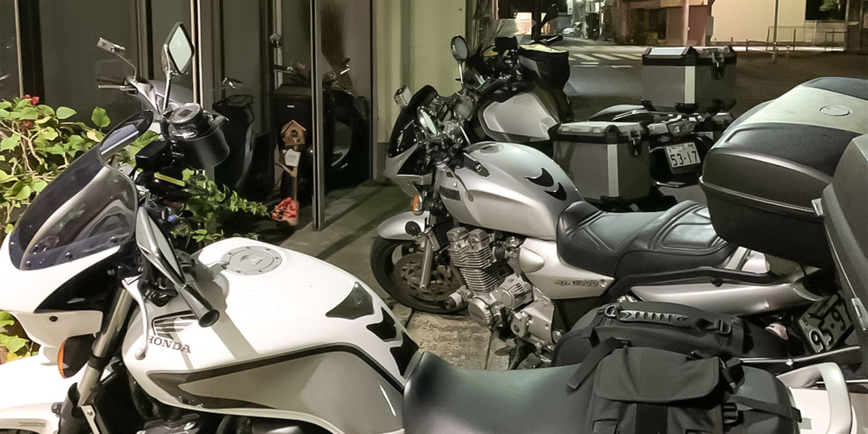 A motorcycle parked in a covered area with a helmet and a bag on the seat.