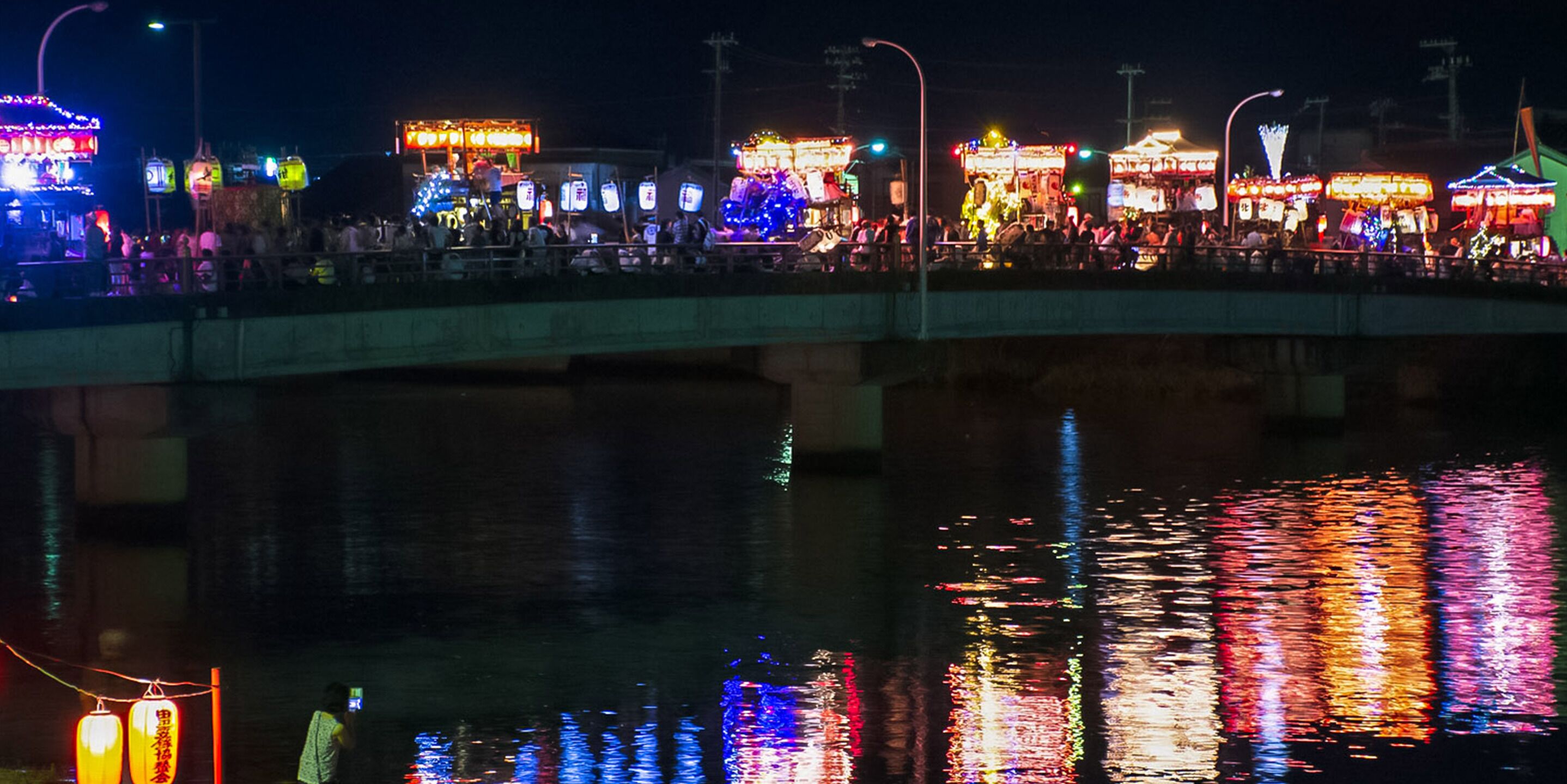 Un puente con luces de colores reflejándose en el agua.