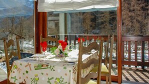 Ein Essbereich mit Tisch für zwei Personen, Tischdecke mit Zeichentrickfiguren und Blick auf eine verschneite Landschaft durch große Fenster.