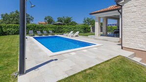 A rectangular swimming pool with a tiled deck, surrounded by a grassy lawn and a stone wall. - Stunning private villa for 6 guests with WIFI, A/C, private pool, TV and terrace (Porec)