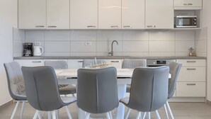 A modern kitchen with white cabinets, a built-in microwave, and a coffee maker. There is a dining table with four chairs. - Stunning private villa for 6 guests with WIFI, A/C, private pool, TV and terrace (Porec)