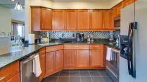 A modern kitchen with wooden cabinets, stainless steel appliances, and a tiled backsplash.