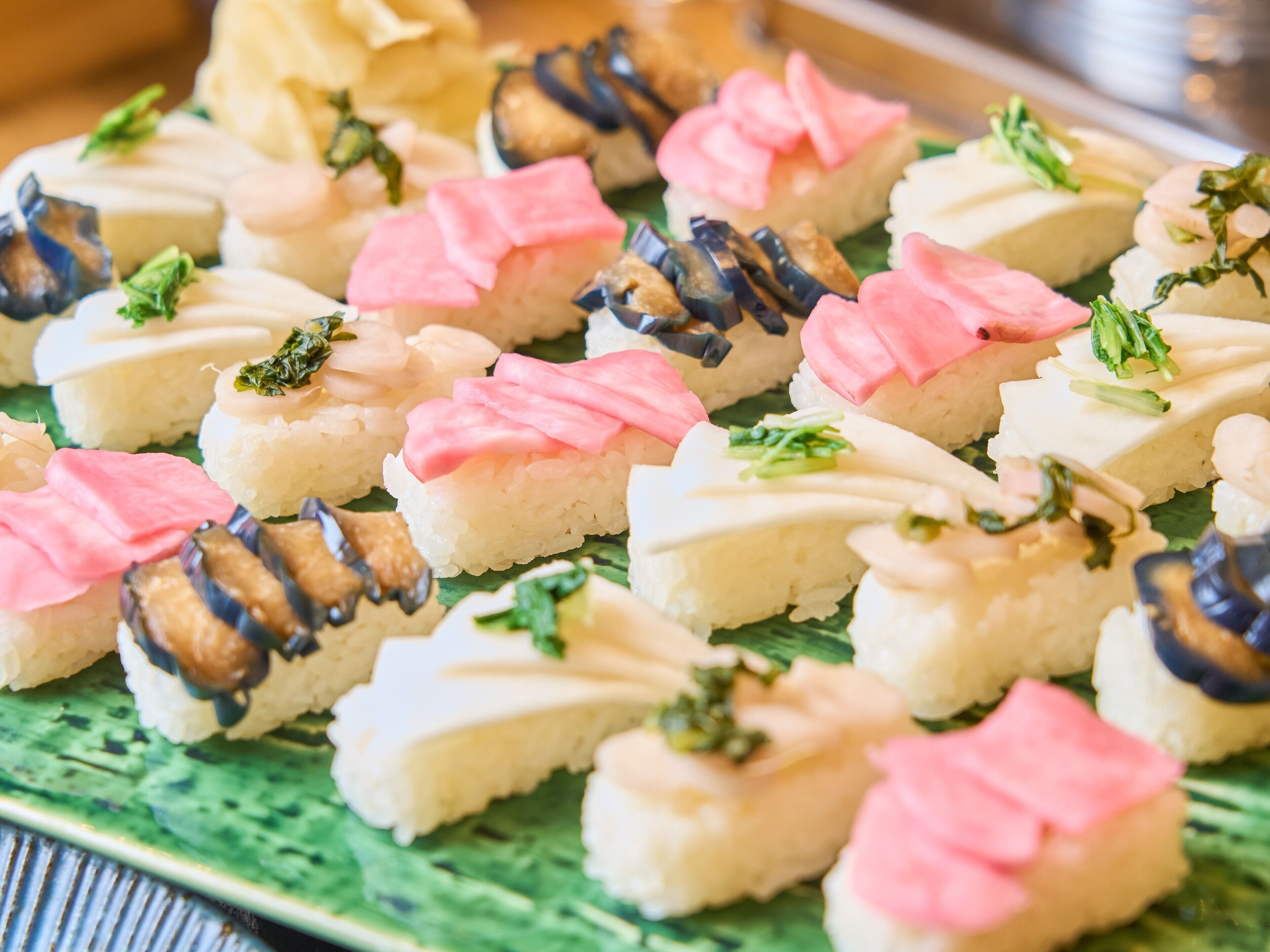Variedad de piezas de sushi dispuestas sobre un plato verde.