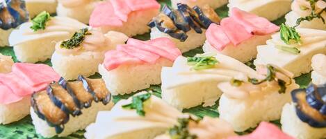 A variety of sushi pieces arranged on a green plate.