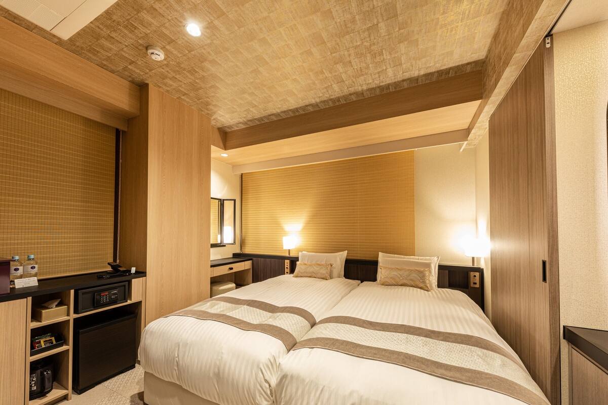 Ein Hotelzimmer mit einem großen Bett, einem Schreibtisch mit Computer und einem Kleiderschrank.
