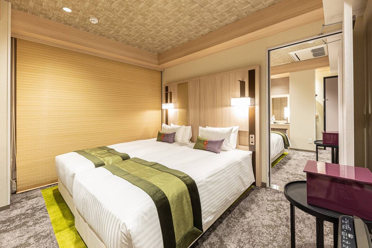 Ein Hotelzimmer mit einem großen Bett, einem Nachttisch, einem Spiegel und einem kleinen Schreibtisch mit Stuhl.