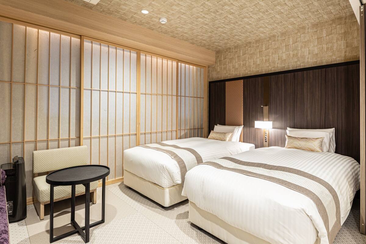 Ein Hotelzimmer mit zwei Betten, einem kleinen Tisch und einem Sessel.