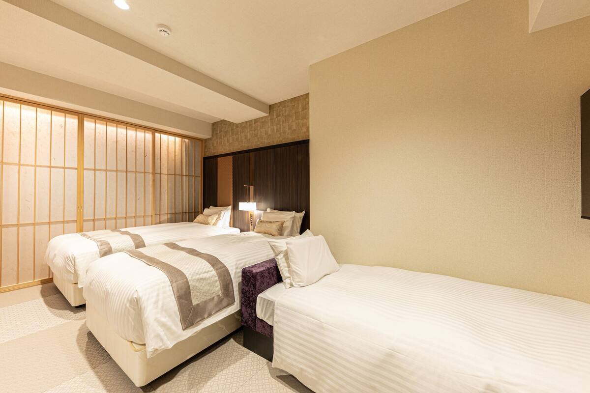 Ein Hotelzimmer mit zwei Betten, einem großen Fenster mit Blick und einer traditionellen japanischen Schiebetür.