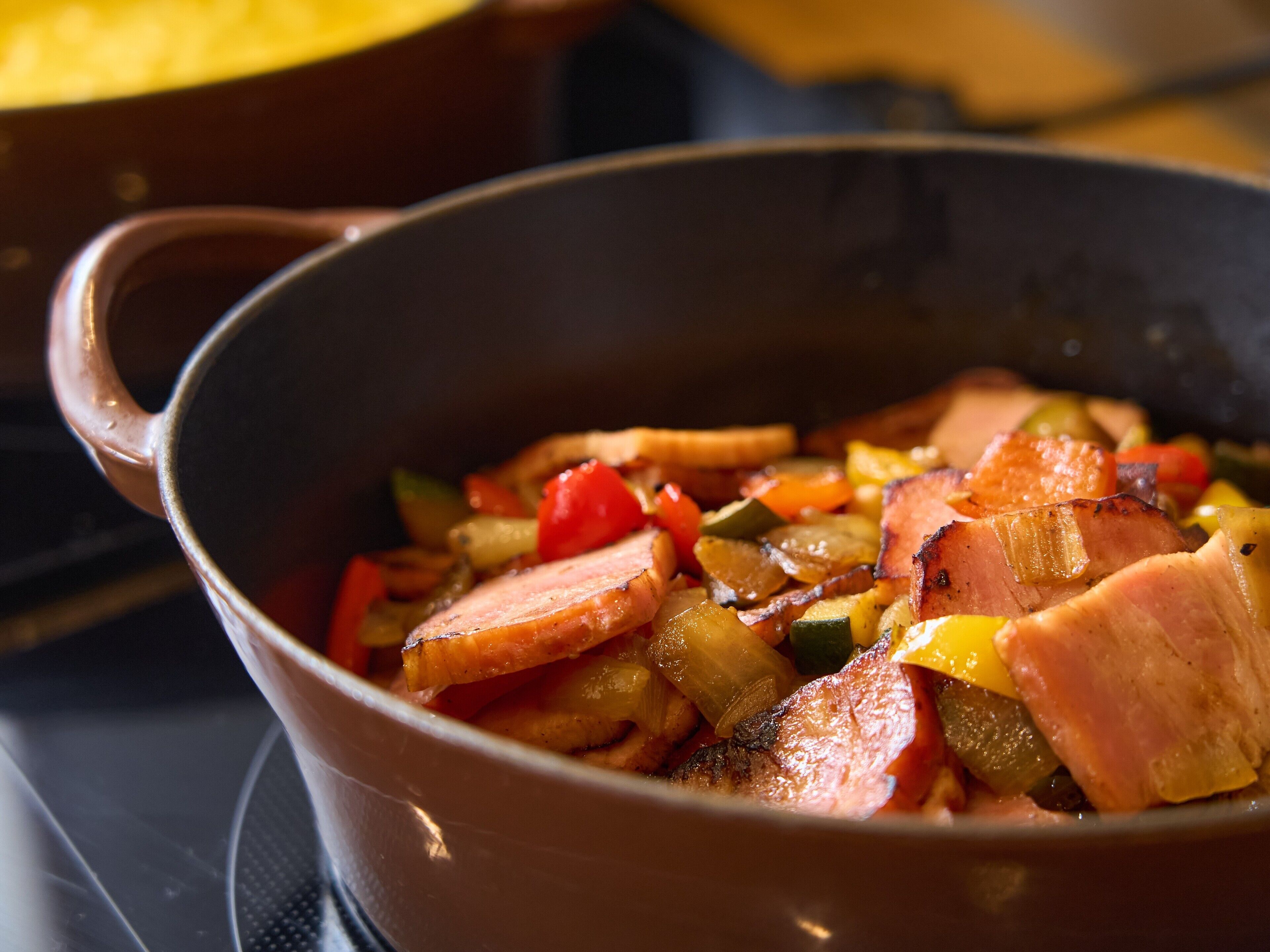 Nahaufnahme einer Bratpfanne mit geschnittenem Schinken und Gemüse.