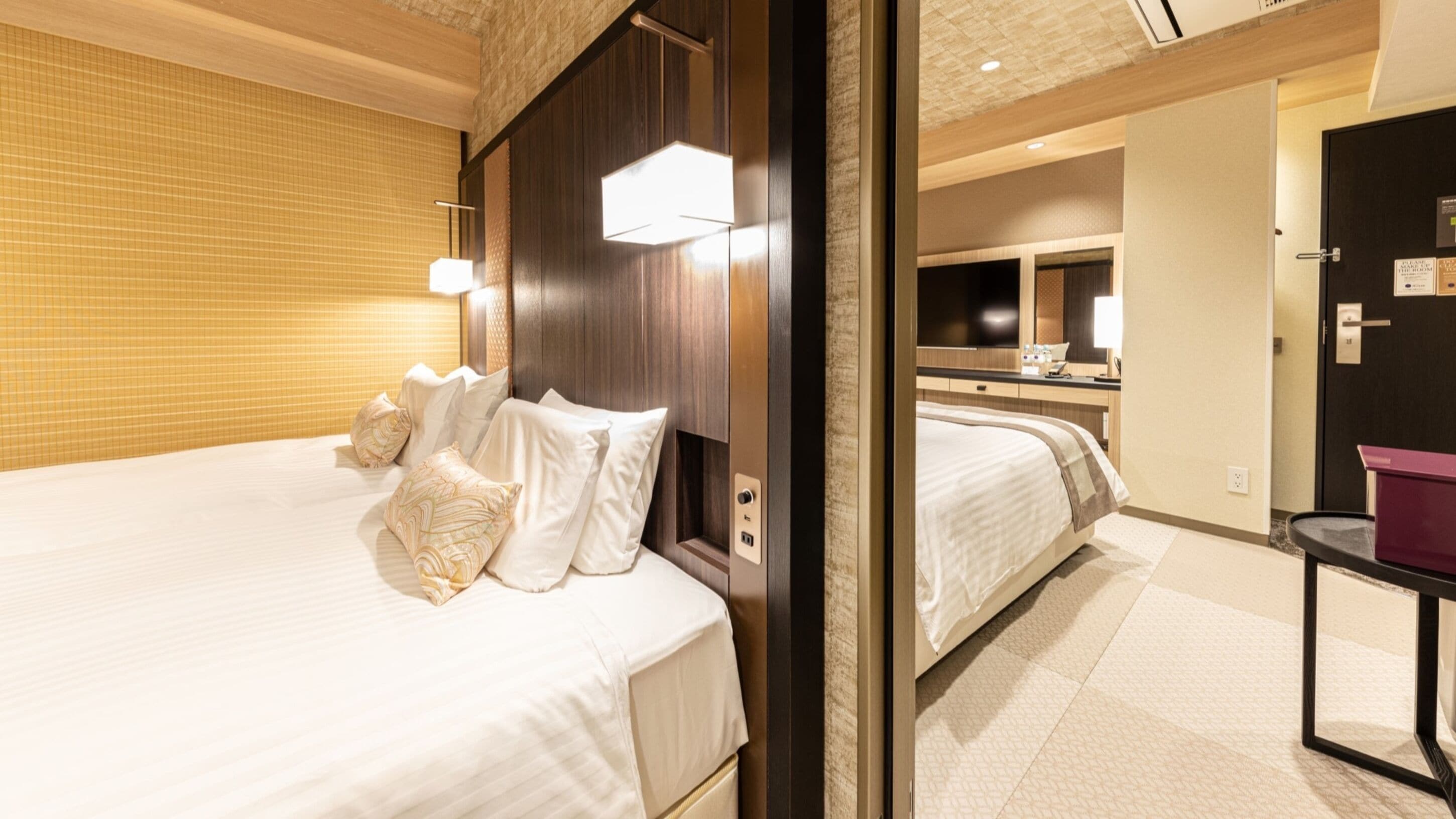 Een hotelkamer met een groot bed, een nachtkastje, een spiegel en een badkamer die door een open deur zichtbaar is.