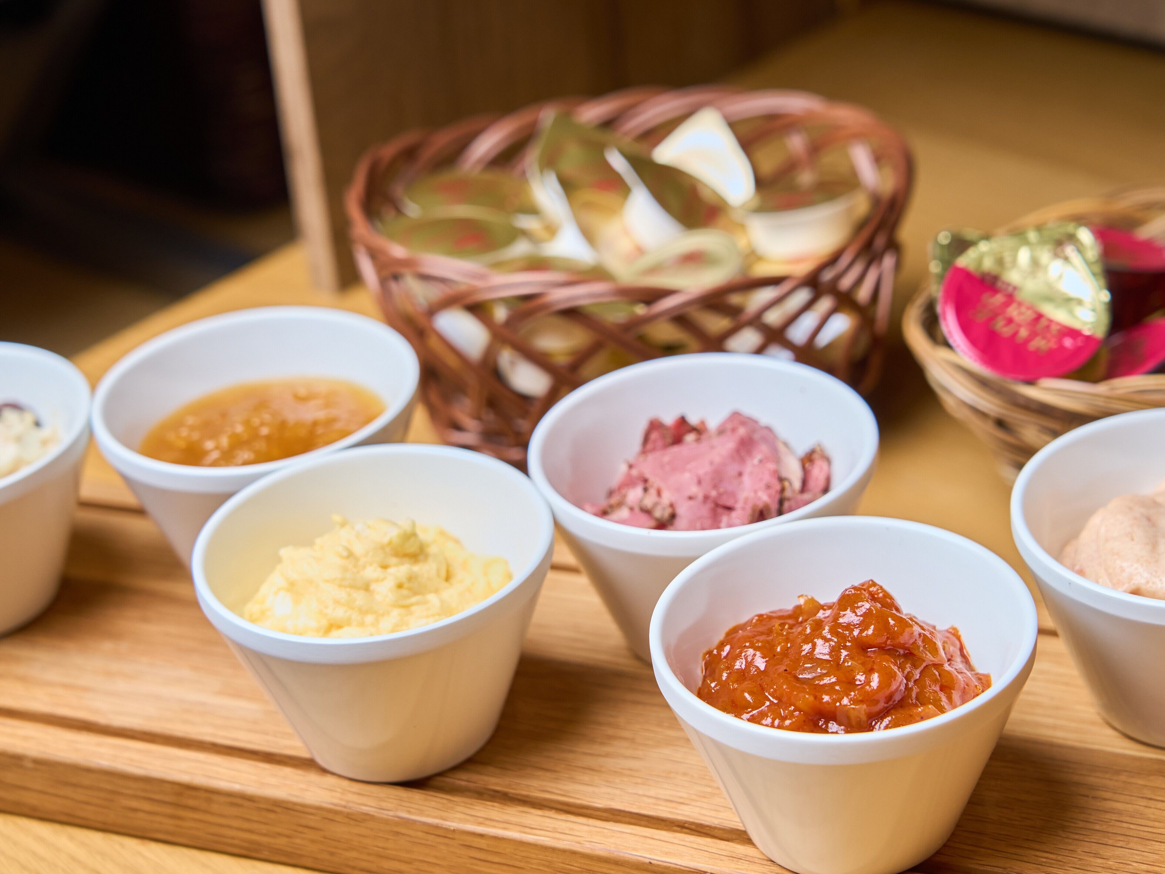 A wooden table with several paper cups containing different food items.