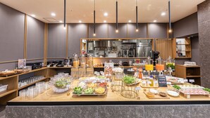 A buffet setup with various food items and beverages, a kitchen area in the background, and modern lighting fixtures. - Hotel Musse Kyoto Shijo Kawaramachi Meitetsu (Kyoto)