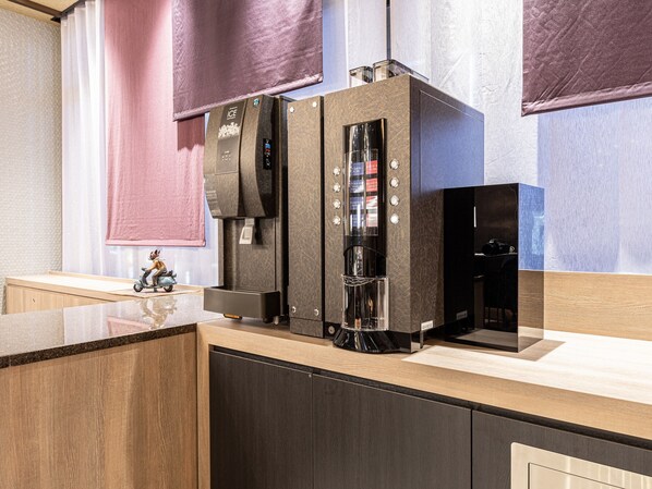 A modern kitchen with a built-in coffee machine, a small refrigerator, and a wooden countertop.