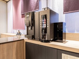 A modern kitchen with a built-in coffee machine, a small refrigerator, and a wooden countertop.