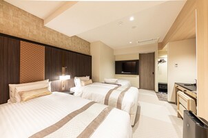 A hotel room with two beds, a desk, a TV, and a minibar.