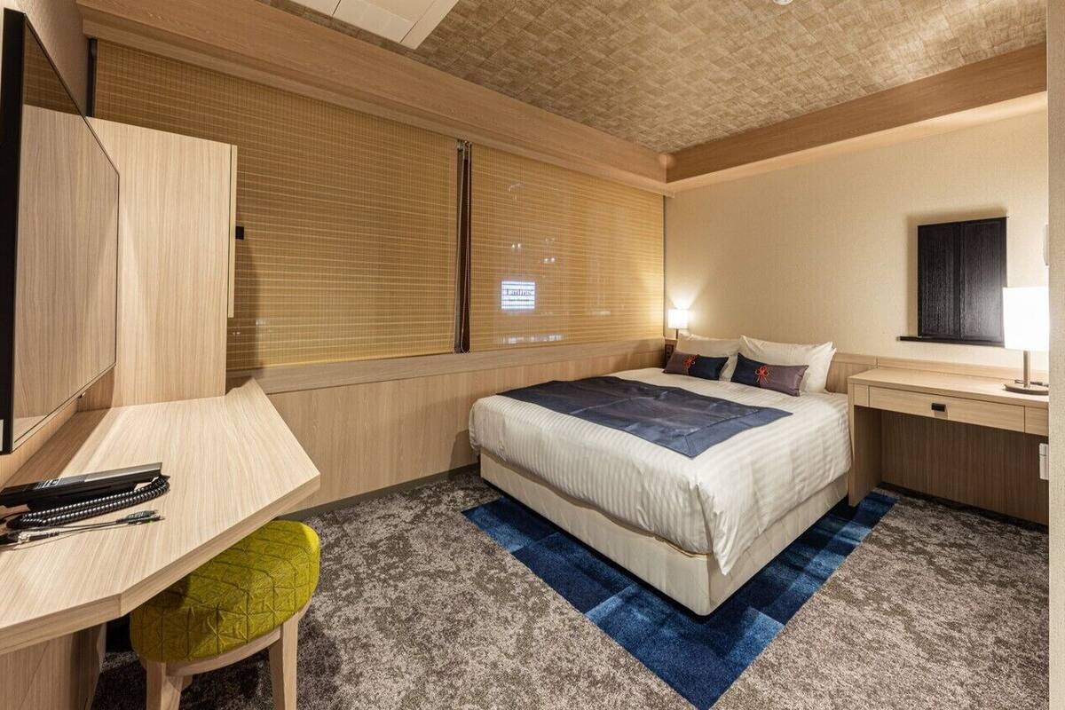 Ein Hotelzimmer mit Bett, Schreibtisch, Stuhl und Fernseher.