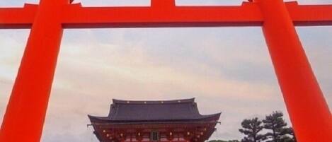 A traditional Japanese building with a prominent red torii gate in the foreground.