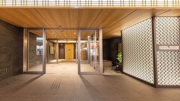 The entrance of Hotel Musse with a modern design, featuring a wooden ceiling, glass doors, and a patterned wall. - Hotel Musse Kyoto Shijo Kawaramachi Meitetsu (Kyoto)