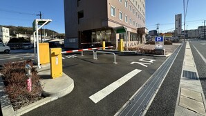 Entrada de hotel con camino de acceso porticado, señal de estacionamiento y paso de peatones.